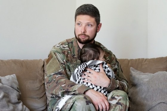 لاري هيبرت جندي في الخدمة الفعلية بالجيش الأمريكي مع ابنته ملفوفة بالكوفية 